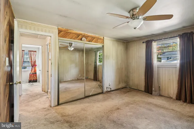 an empty room with closet and a chandelier fan