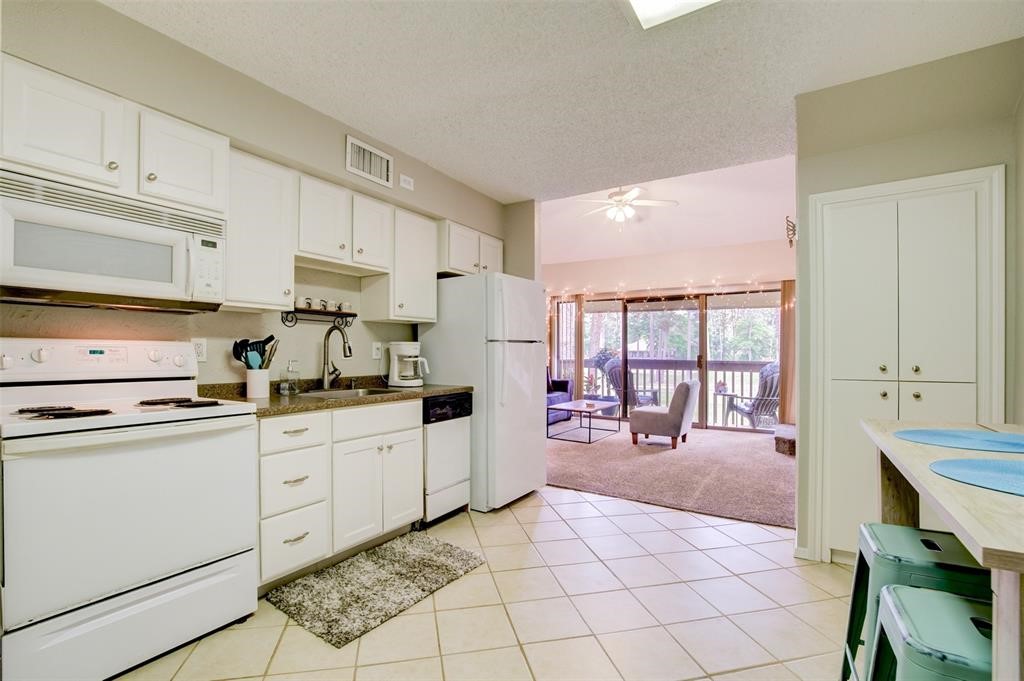 12900 Walden Road, Unit 202B Montgomery, TX 77356 - Photo 13 of 30 a kitchen with white cabinets a sink dishwasher and a stove with wooden floors