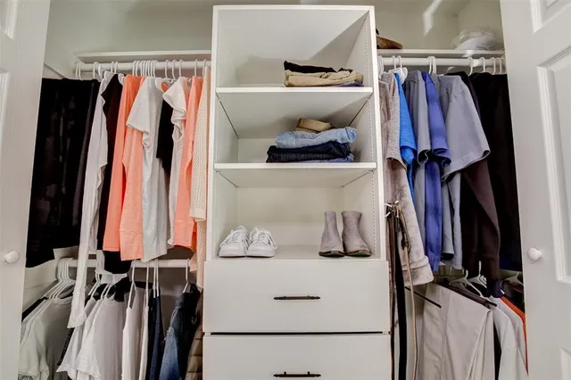 a view of walk in closet with clothes and shoes