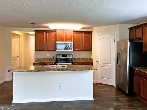 a kitchen with stainless steel appliances granite countertop a refrigerator a stove a sink and a microwave