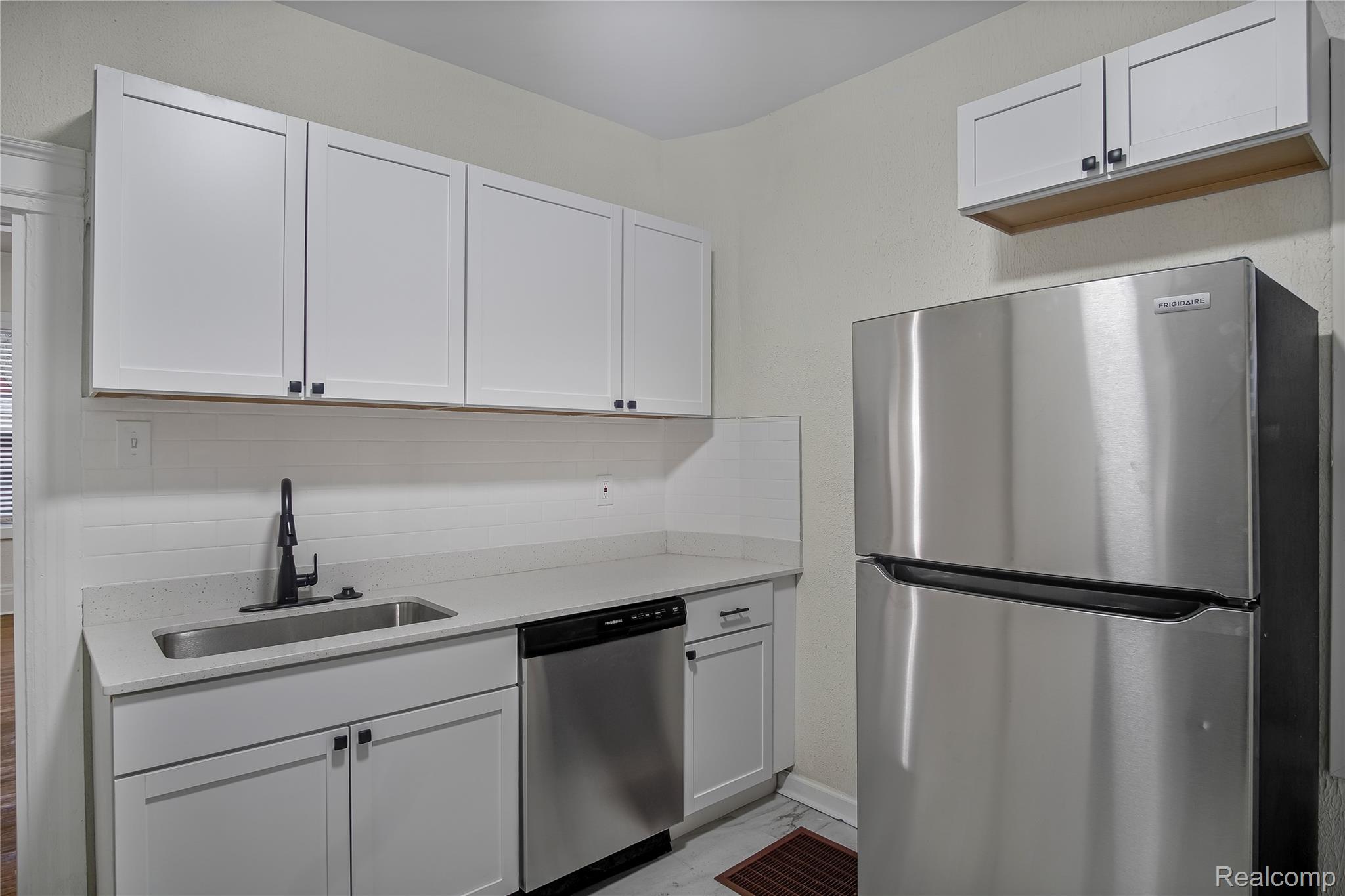 427 Melbourne Street Detroit, MI 48202 - Photo 6 of 29 Kitchen featuring appliances with stainless steel finishes, white cabinetry, backsplash, light marble finish floors, and light stone countertops