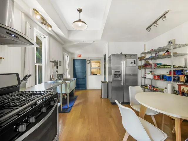 a kitchen with stainless steel appliances a stove a refrigerator and a dining table