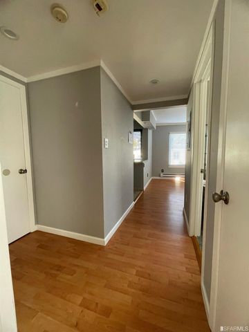 a view of a hallway with wooden floor and a bathroom