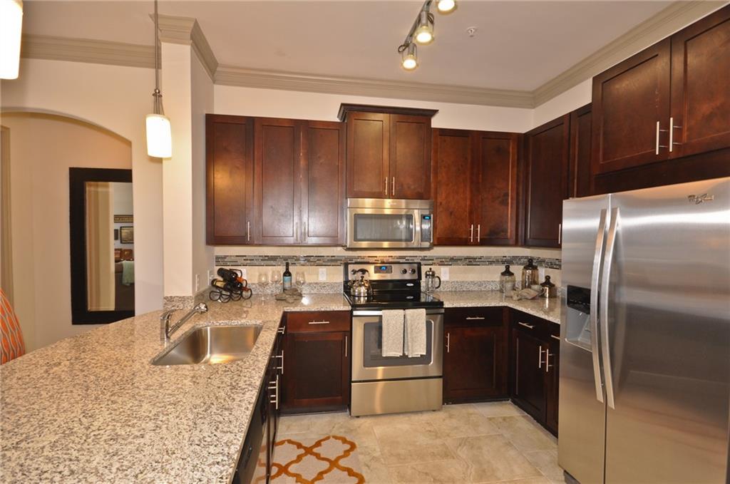 3695 Cumberland Boulevard Southeast, Unit 1129 Atlanta, GA 30339 - Photo 2 of 34 a kitchen with stainless steel appliances granite countertop a stove a sink a refrigerator and a microwave