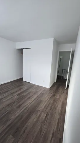 a view of an empty room with wooden floor and stairs
