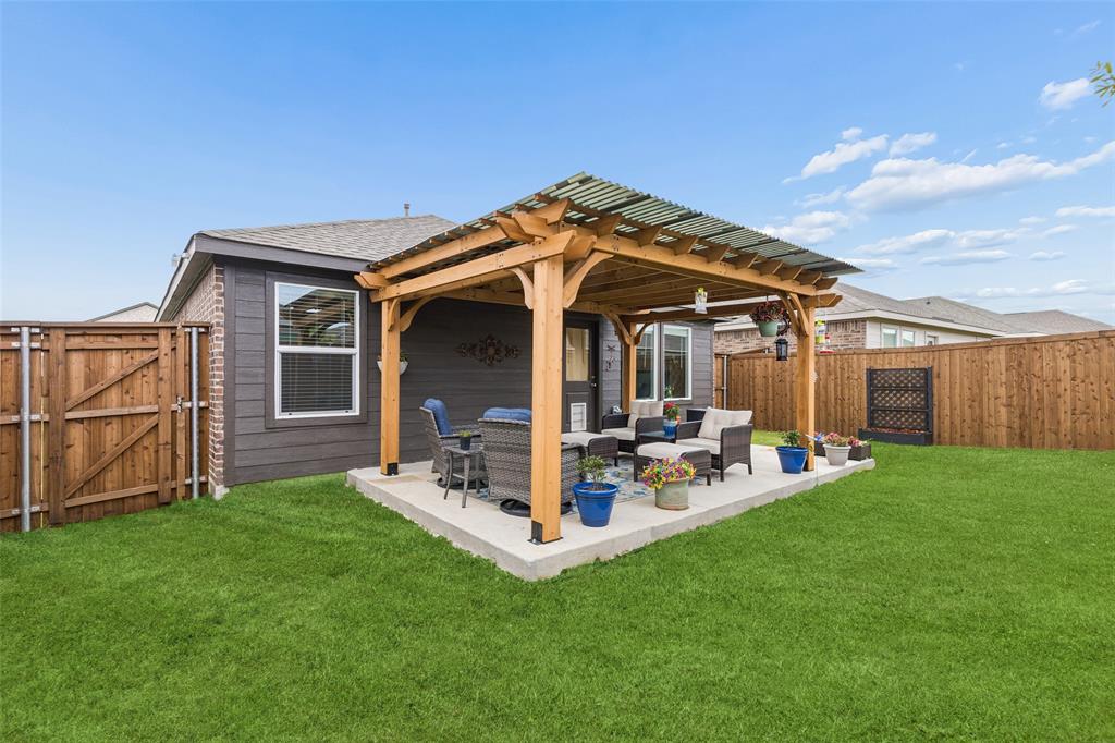 14163 Kempt Drive Pilot Point, TX 76258 - Photo 19 of 29 Designed for outdoor living, this backyard showcases a custom pergola-covered patio and an extended concrete pad added by the sellers, creating an ideal space for entertaining guests, enjoying weekend barbecues, or unwinding under the Texas sky. The spacious, fully fenced yard offers plenty of room for pets, play, and gardening.