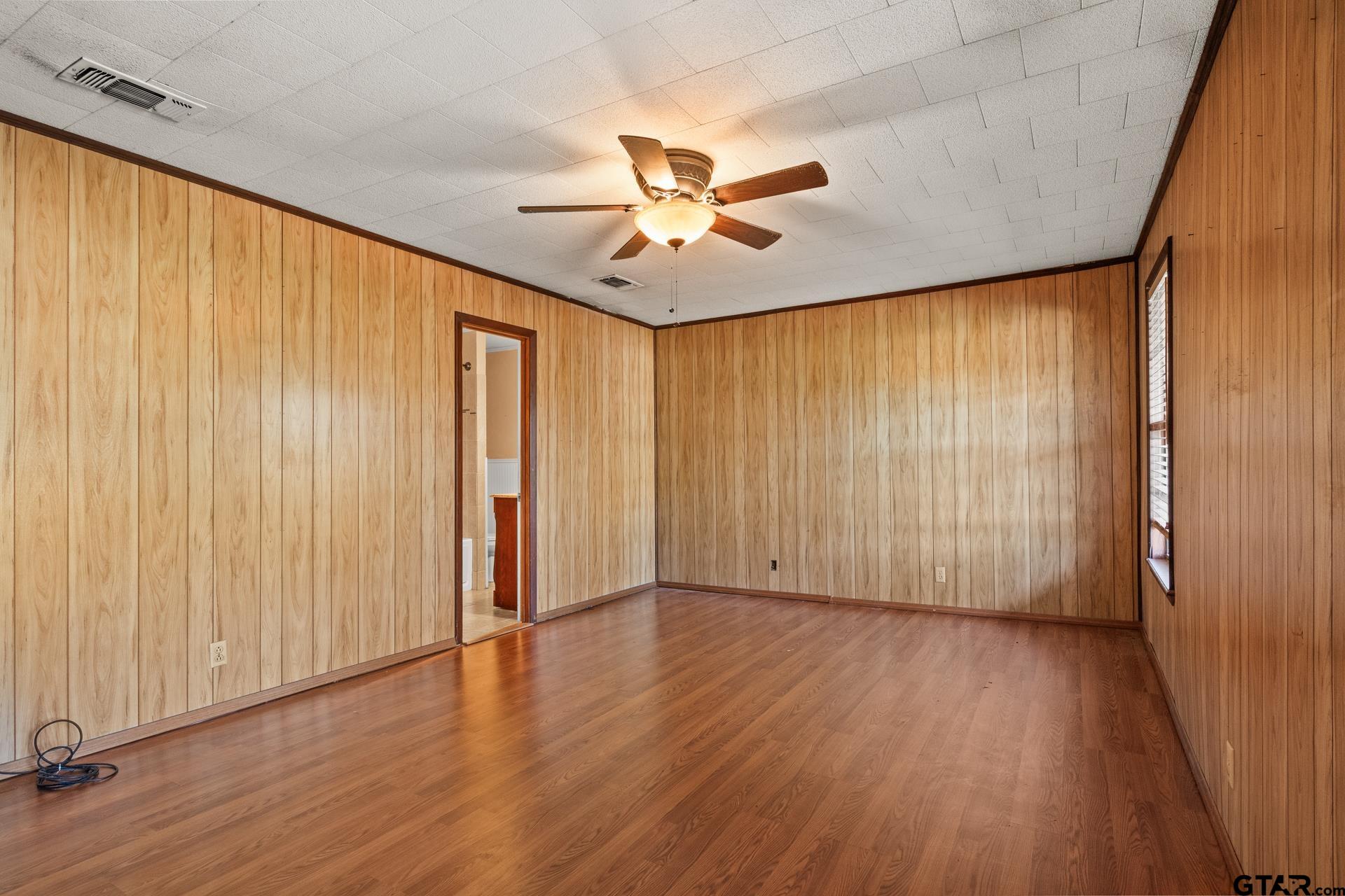 302 Smith Street Naples, TX 75568 - Photo 11 of 28 an empty room with wooden floor fan and windows