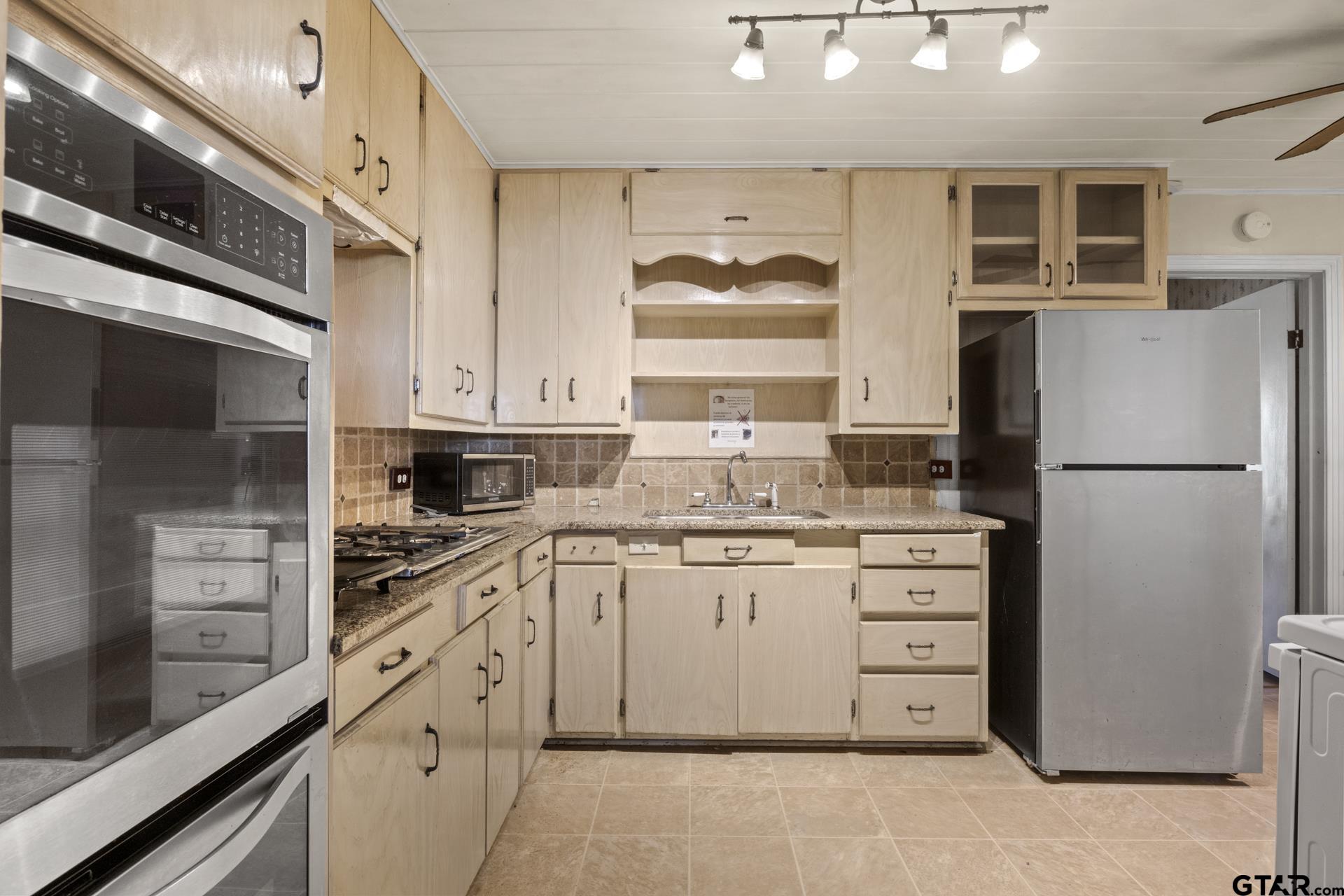 302 Smith Street Naples, TX 75568 - Photo 4 of 28 a kitchen with stainless steel appliances a refrigerator stove and sink