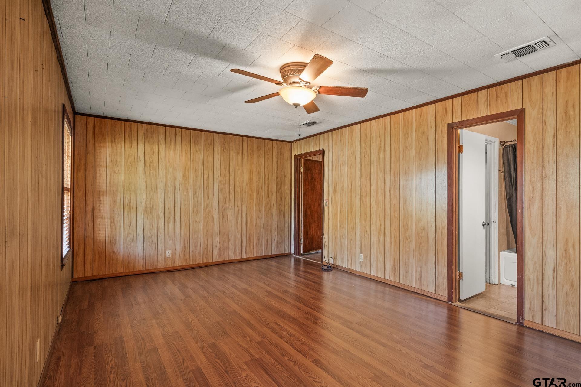302 Smith Street Naples, TX 75568 - Photo 10 of 28 an empty room with wooden floor chandelier fan and windows
