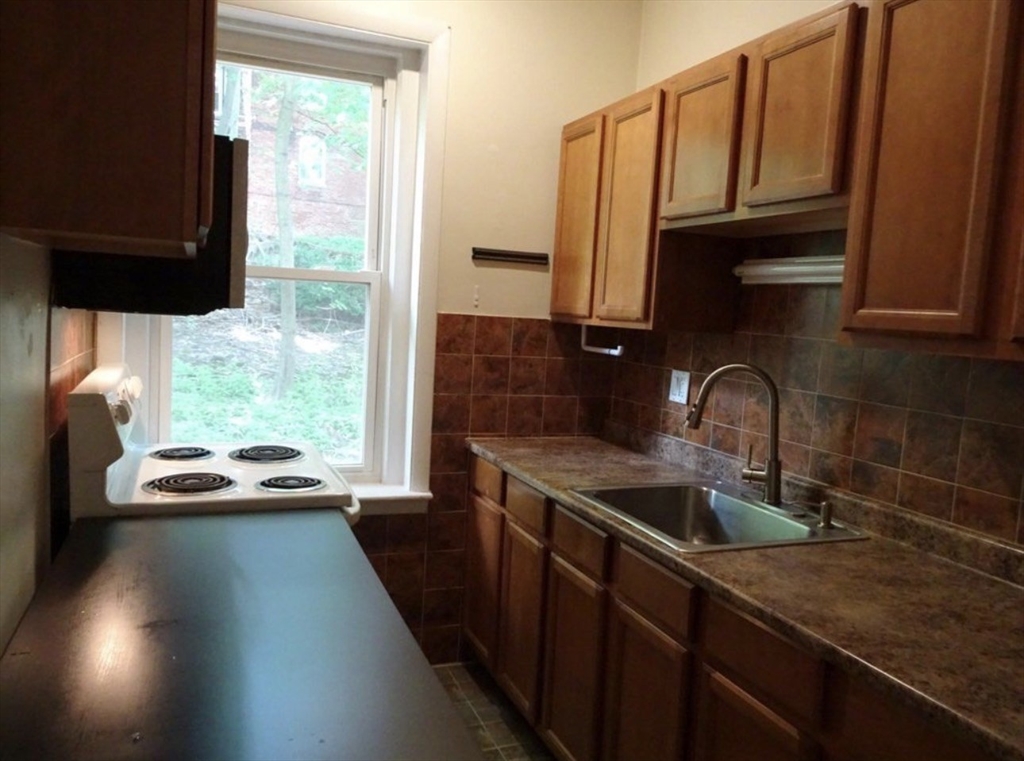 a kitchen with stainless steel appliances granite countertop a sink a stove and a refrigerator