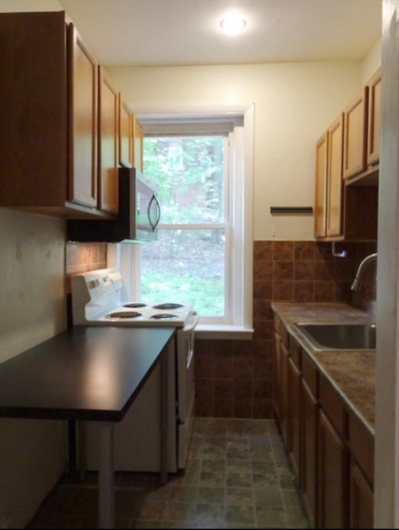 15 University, Unit 22 Brookline, MA 02445 - Photo 2 of 10 a kitchen with stainless steel appliances granite countertop a sink a stove and a microwave