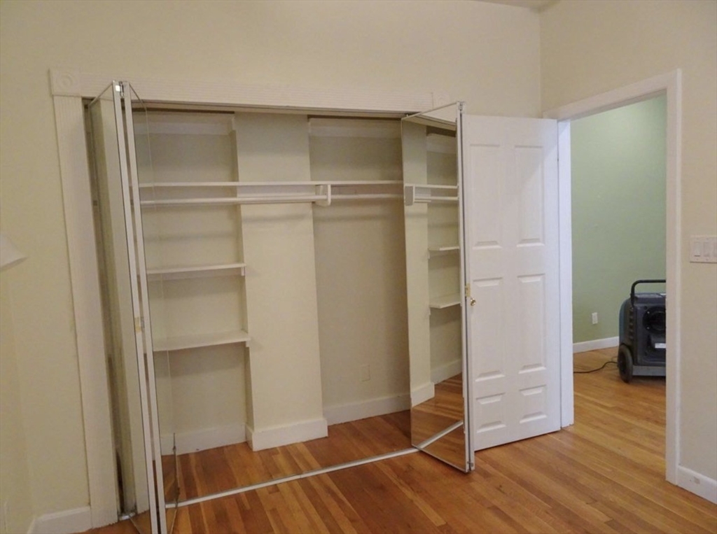 15 University, Unit 22 Brookline, MA 02445 - Photo 6 of 10 a room with walk in closet and wooden floor