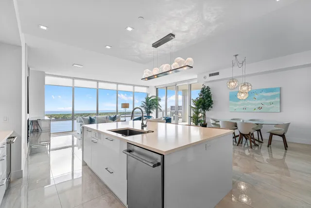a kitchen with kitchen island a sink a counter top space appliances and a dining table view