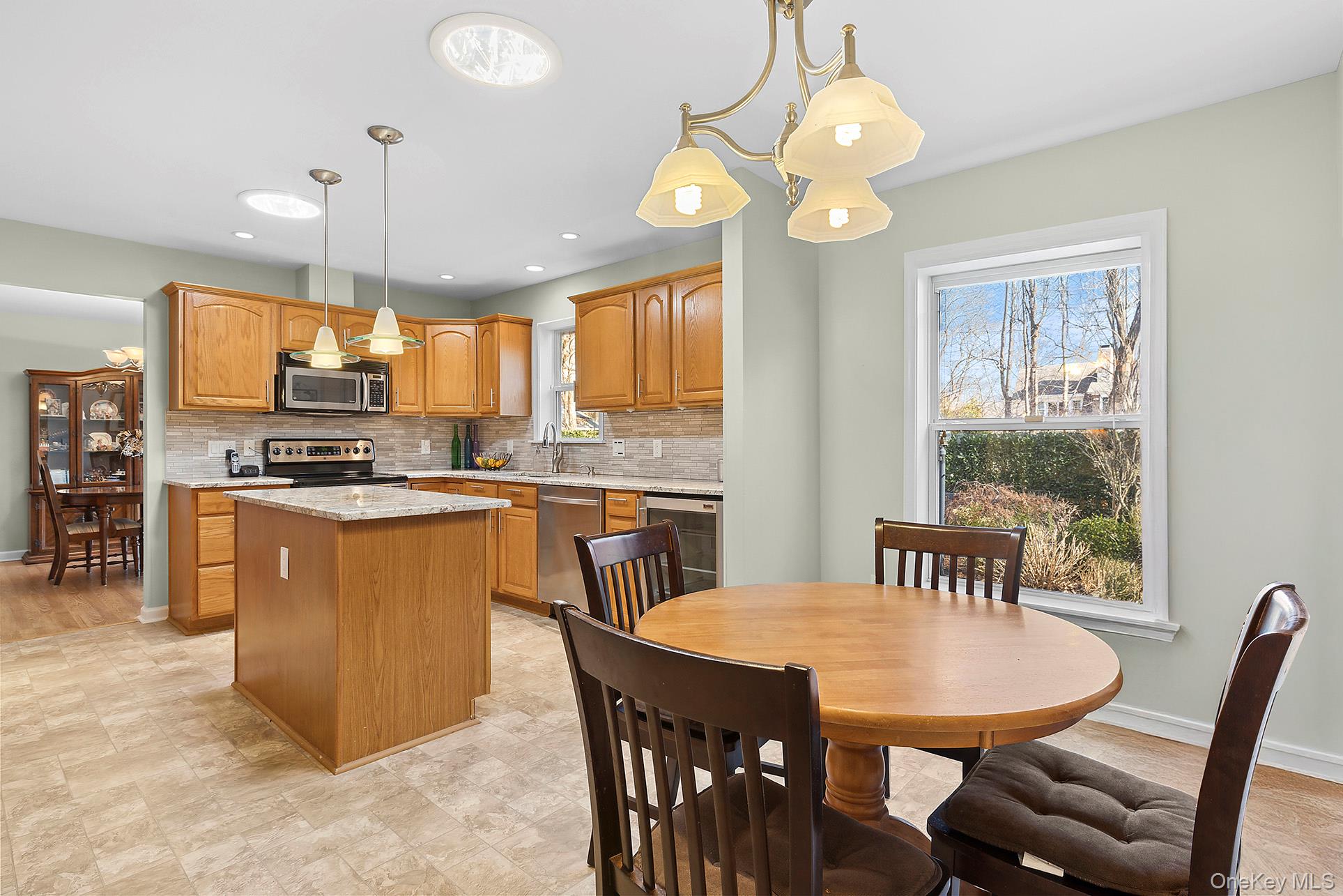 17 Cove View Road Sag Harbor, NY 11963 - Photo 4 of 15 Kitchen with light stone counters, hanging light fixtures, a kitchen island, and appliances with stainless steel finishes