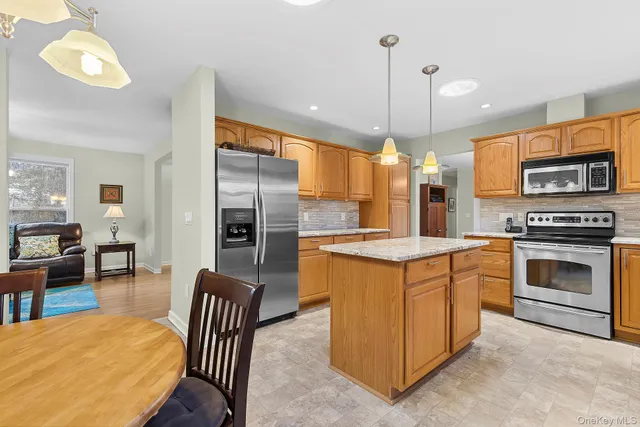 a kitchen with stainless steel appliances granite countertop a stove a sink a refrigerator a dining table and chairs
