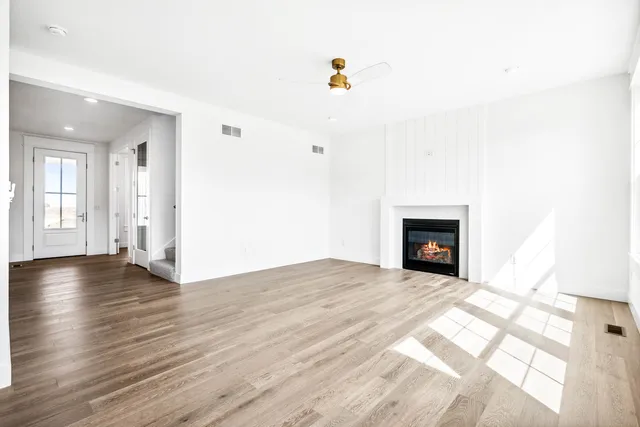 a view of empty room with wooden floor and kitchen view
