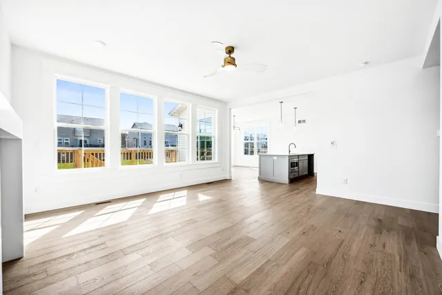 a kitchen with stainless steel appliances granite countertop a sink a refrigerator a stove and white cabinets with wooden floor