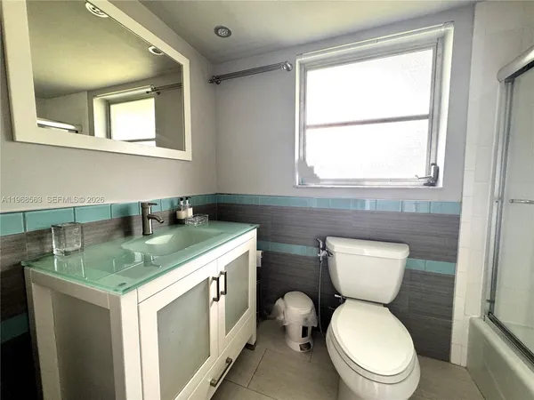 a bathroom with a granite countertop toilet sink and mirror