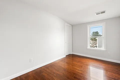 an empty room with wooden floor and window