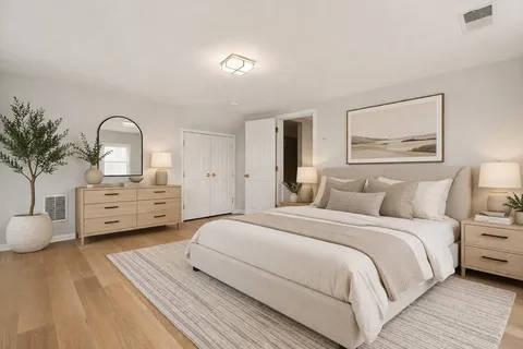 a spacious bedroom with a bed a dresser and potted plants