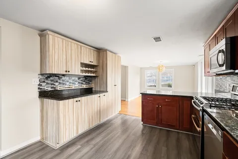 a kitchen with stainless steel appliances a stove a sink cabinets and a window