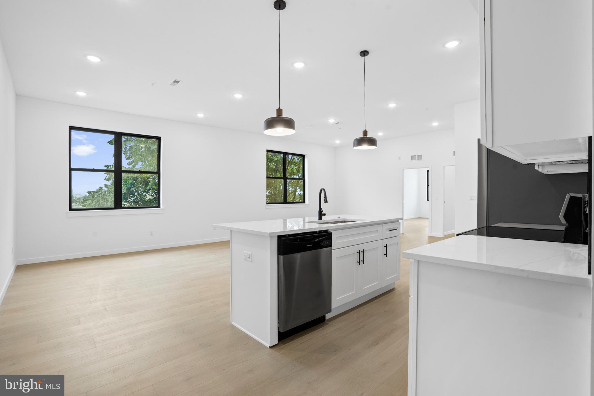 a large kitchen with kitchen island a sink stainless steel appliances and a chandelier
