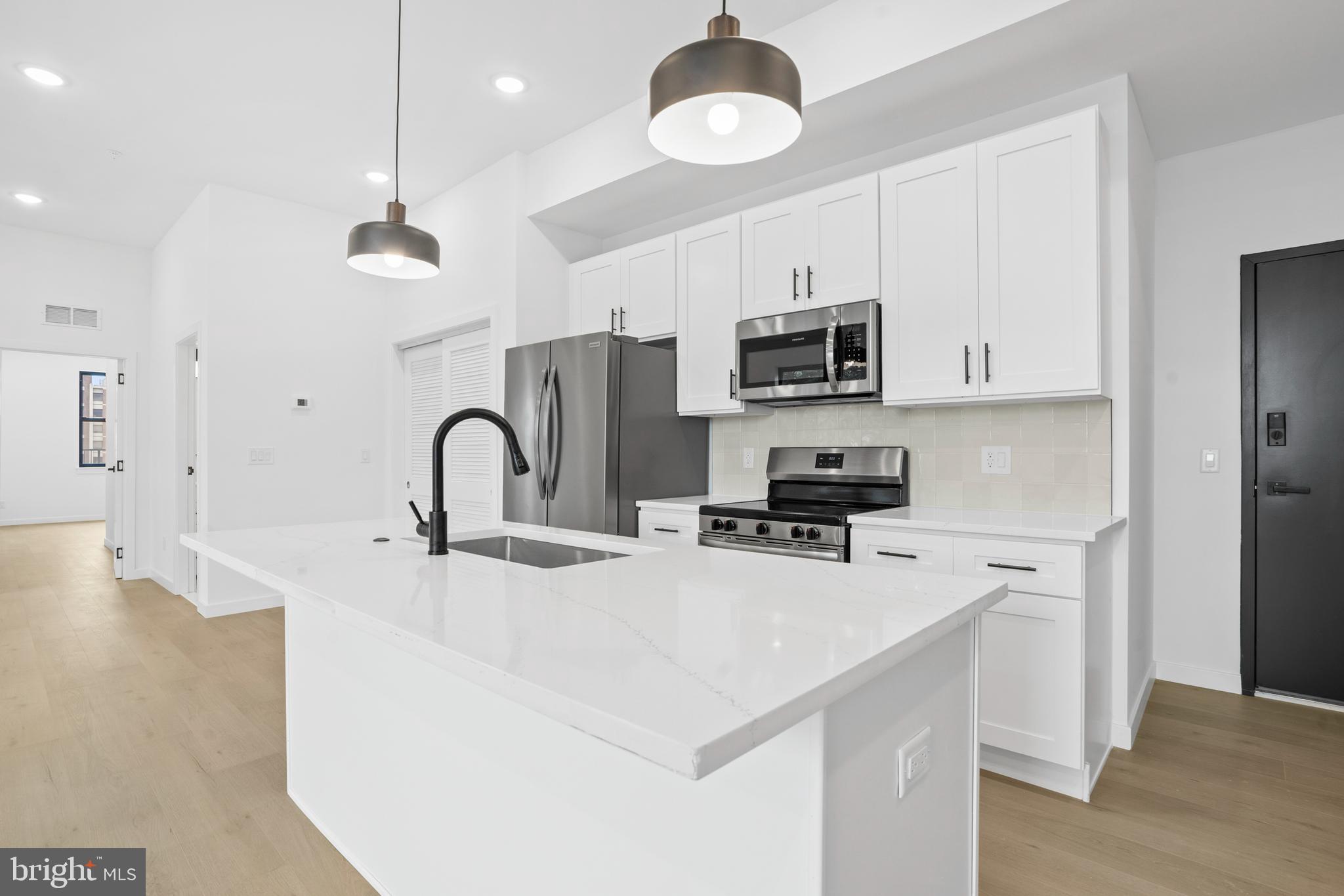 3211 Cedar Street, Unit 402 Philadelphia, PA 19134 - Photo 3 of 21 a kitchen with stainless steel appliances a sink a stove a refrigerator cabinets a center island and stainless steel appliances