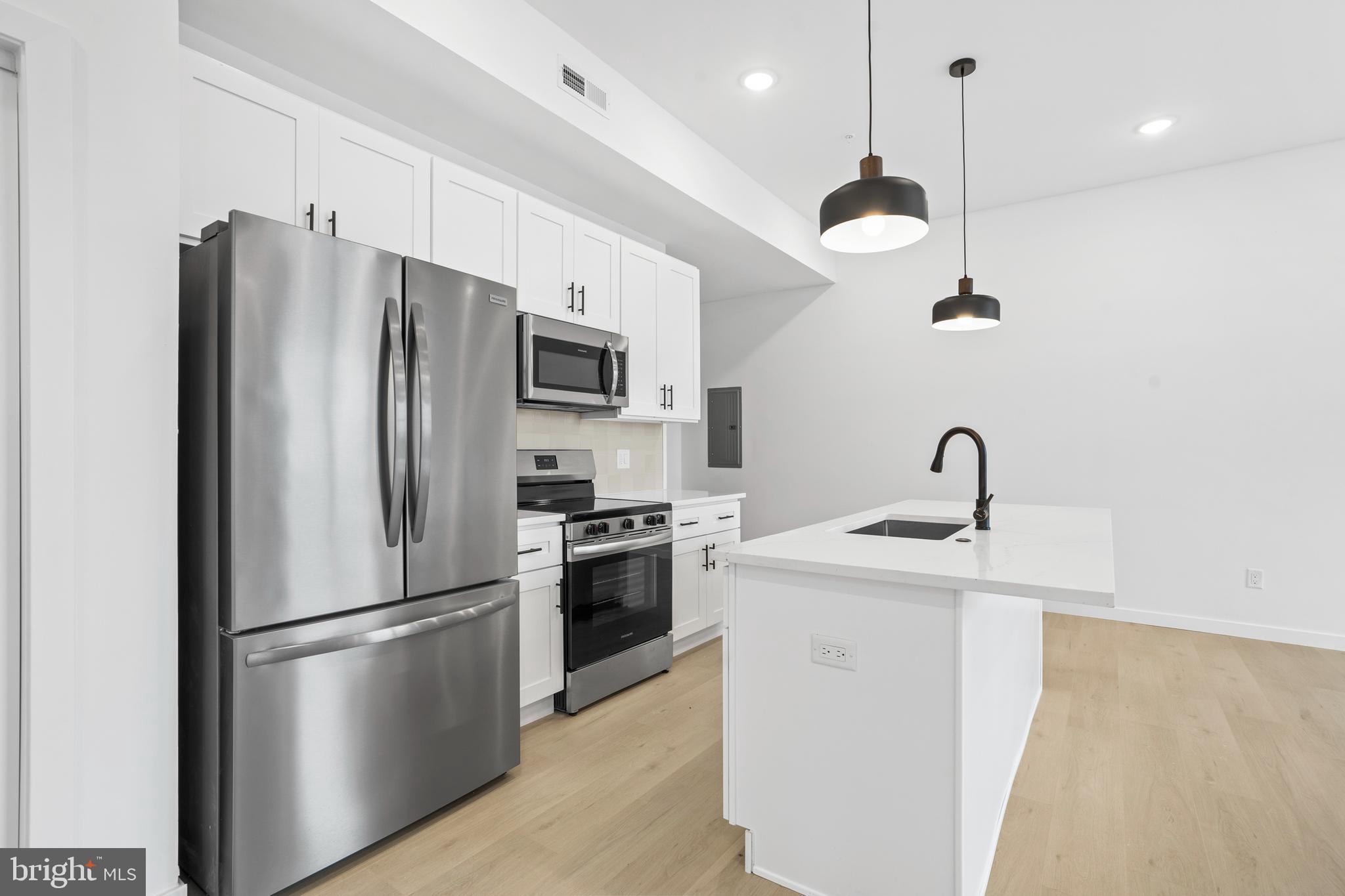 3211 Cedar Street, Unit 402 Philadelphia, PA 19134 - Photo 5 of 21 a kitchen with stainless steel appliances granite countertop a refrigerator a sink a stove and a refrigerator