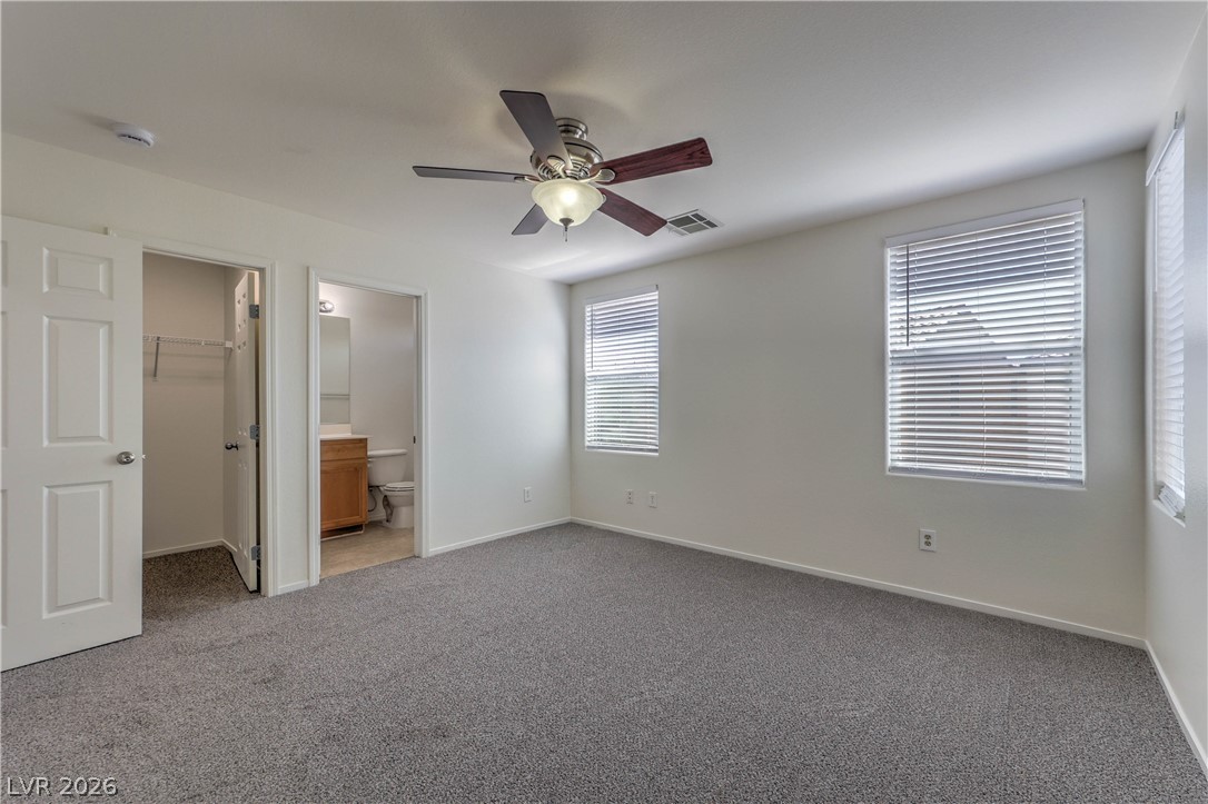 10939 Paradise Road Henderson, NV 89052 - Photo 23 of 36 A well-lit bedroom with ample space, featuring a ceiling fan and access to a private bathroom and walk-in closet.