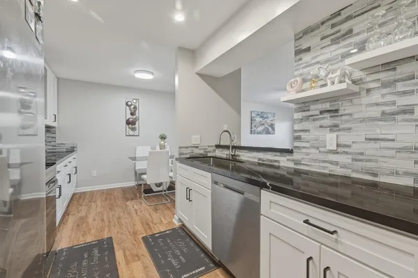 a spacious bathroom with a granite countertop sink a toilet a mirror and a shower