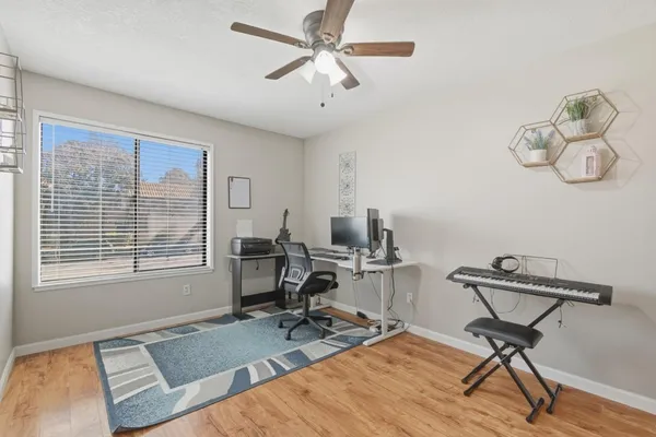 a view of a workspace with furniture and a ceiling fan
