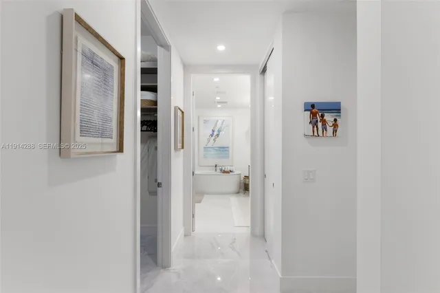 a view of a hallway with wooden floor and a bathroom