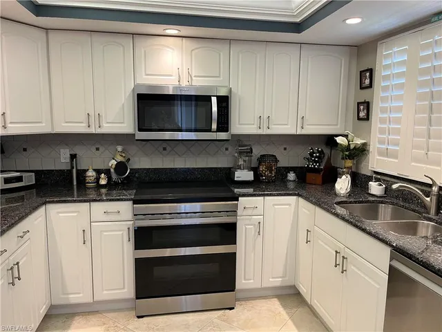 a kitchen with white cabinets and appliances