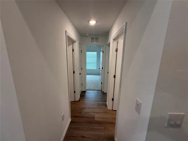 a view of a hallway with wooden floor and a bathroom