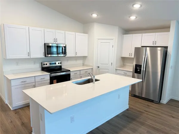 a kitchen with stainless steel appliances a microwave a sink a stove a refrigerator cabinets and a center island