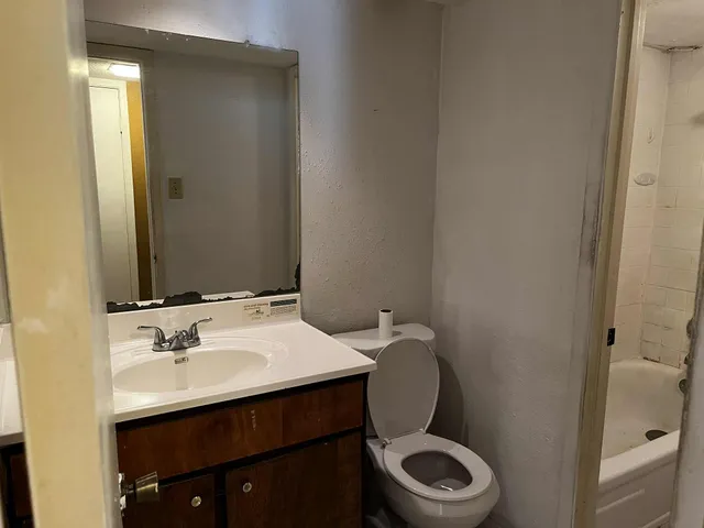 a bathroom with a granite countertop toilet sink and mirror
