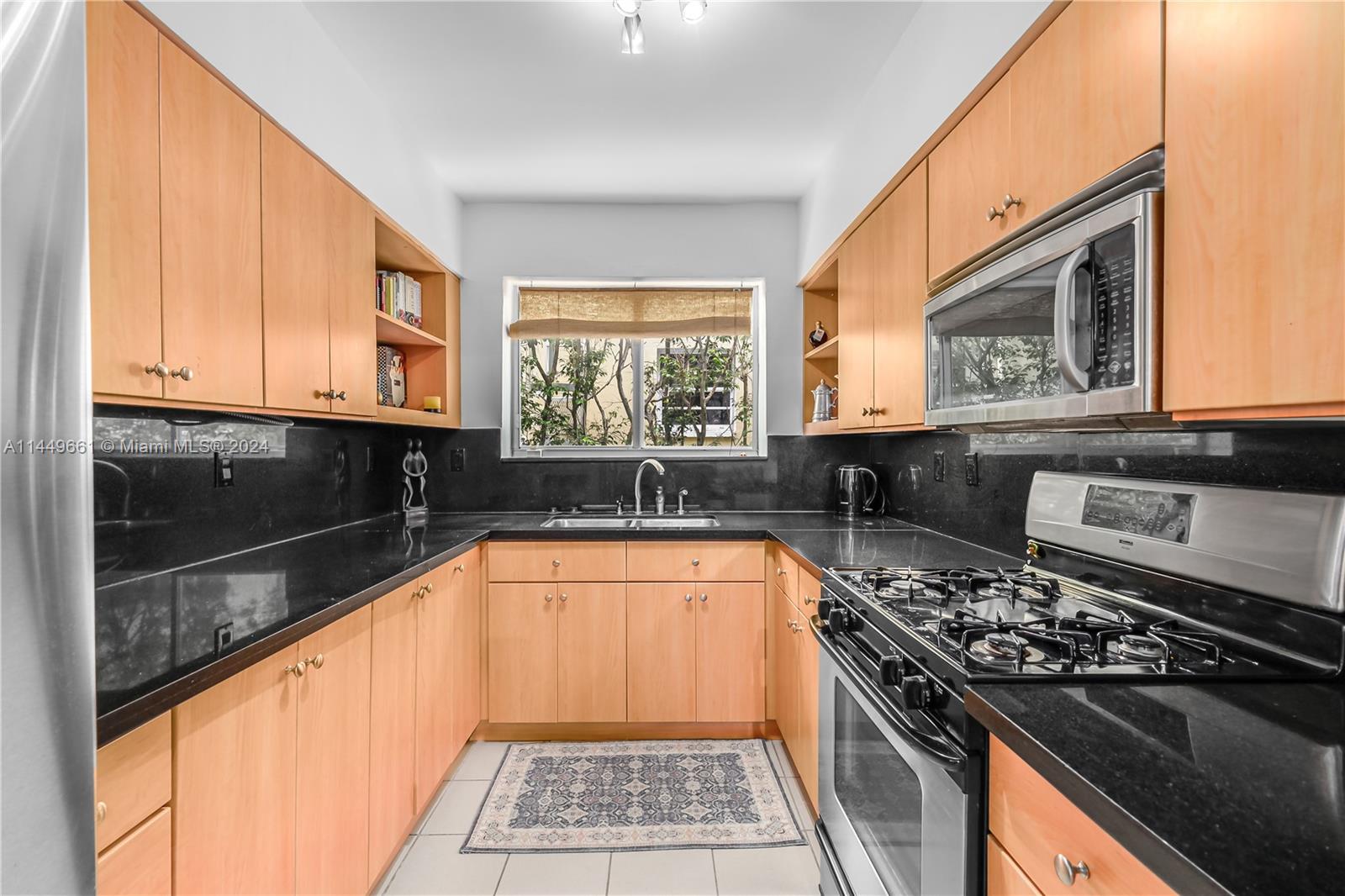 4800 Pine Tree Drive, Unit 101 Miami Beach, FL 33140 - Photo 7 of 30 a kitchen with granite countertop a stove a sink and a microwave