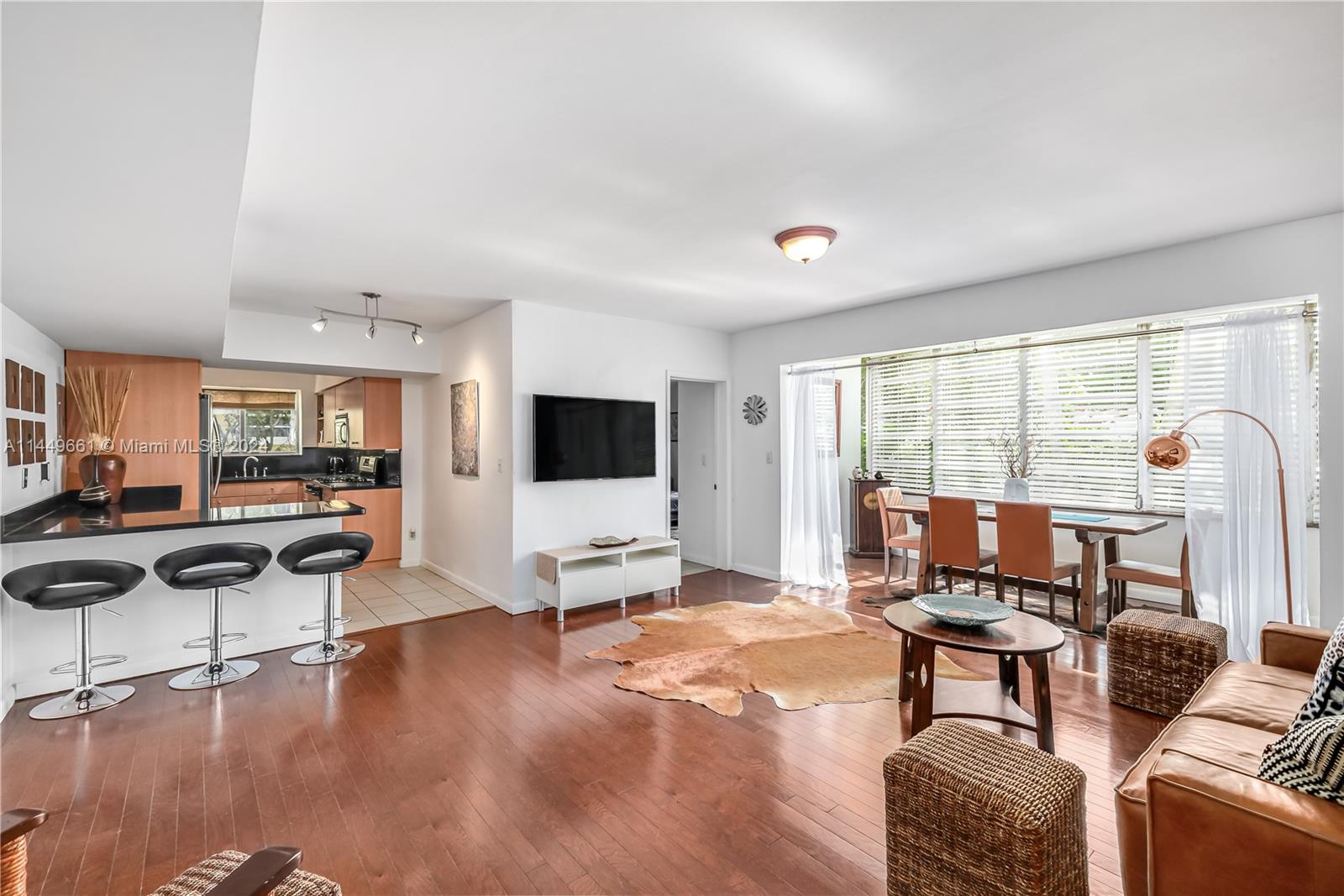 4800 Pine Tree Drive, Unit 101 Miami Beach, FL 33140 - Photo 9 of 30 a living room with furniture and a flat screen tv with kitchen view