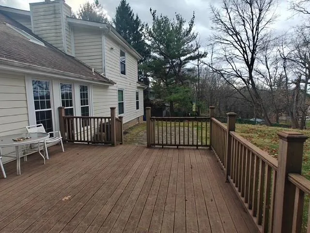 a view of a deck with wooden floor and fence next to a yard