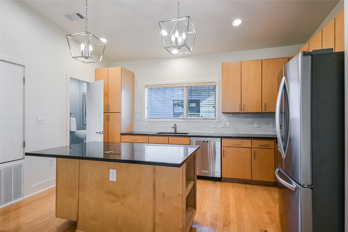1702 South Lamar Boulevard, Unit 22 Austin, TX 78704 - Photo 11 of 30 a kitchen with stainless steel appliances granite countertop a refrigerator a sink dishwasher a stove and a dining table with wooden floor