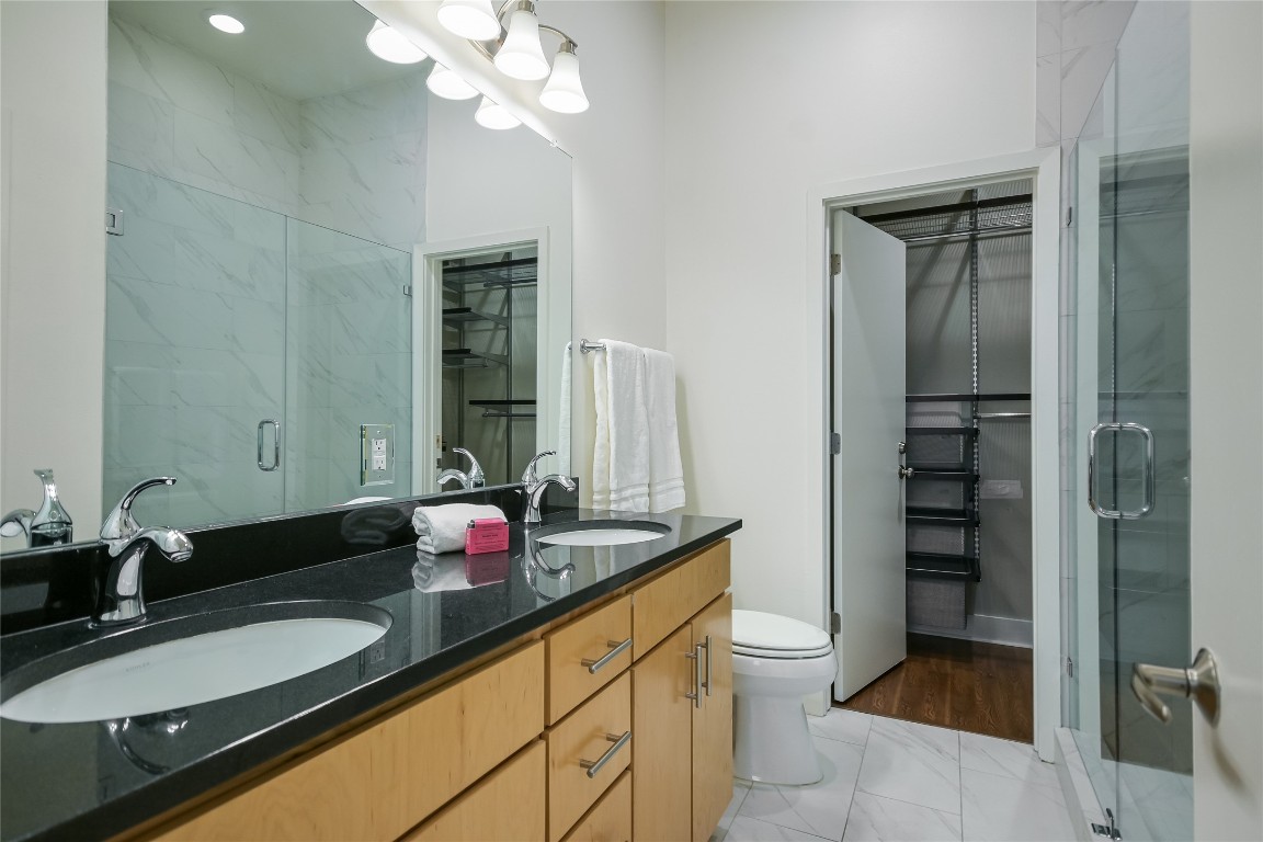 1702 South Lamar Boulevard, Unit 22 Austin, TX 78704 - Photo 16 of 30 a bathroom with a granite countertop sink a toilet and a mirror
