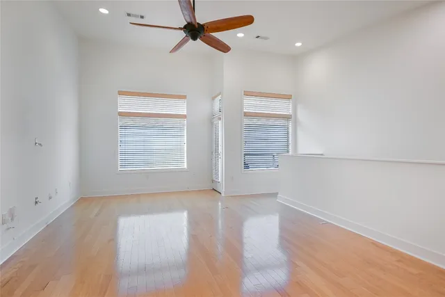 an empty room with windows and fan