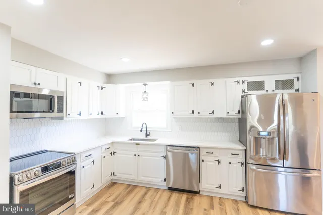a kitchen with granite countertop white cabinets and stainless steel appliances