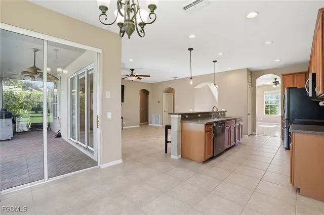a large kitchen with a large counter top stainless steel appliances and chandelier