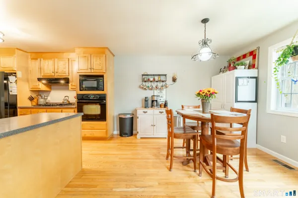 a kitchen with stainless steel appliances kitchen island granite countertop a table chairs sink and cabinets