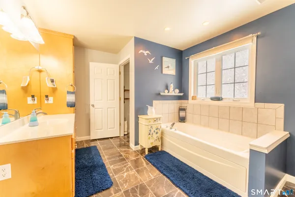 a bathroom with a tub sink and mirror