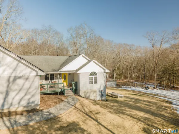 a view of a white house with a large trees next to a road