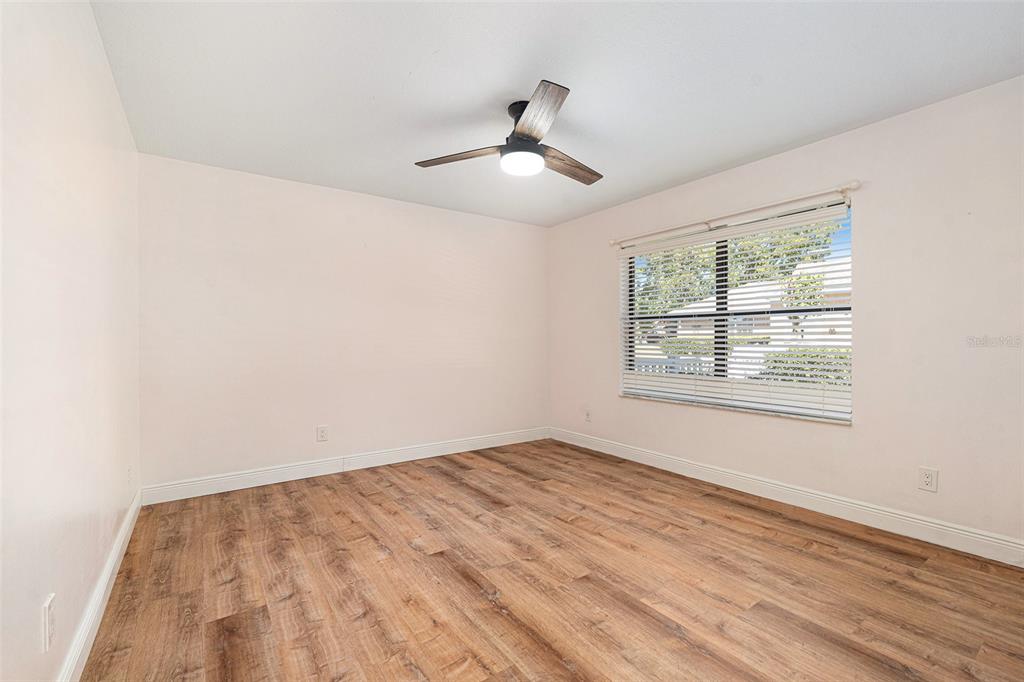 175 Pine Street Homosassa, FL 34446 - Photo 19 of 27 an empty room with wooden floor chandelier fan and windows