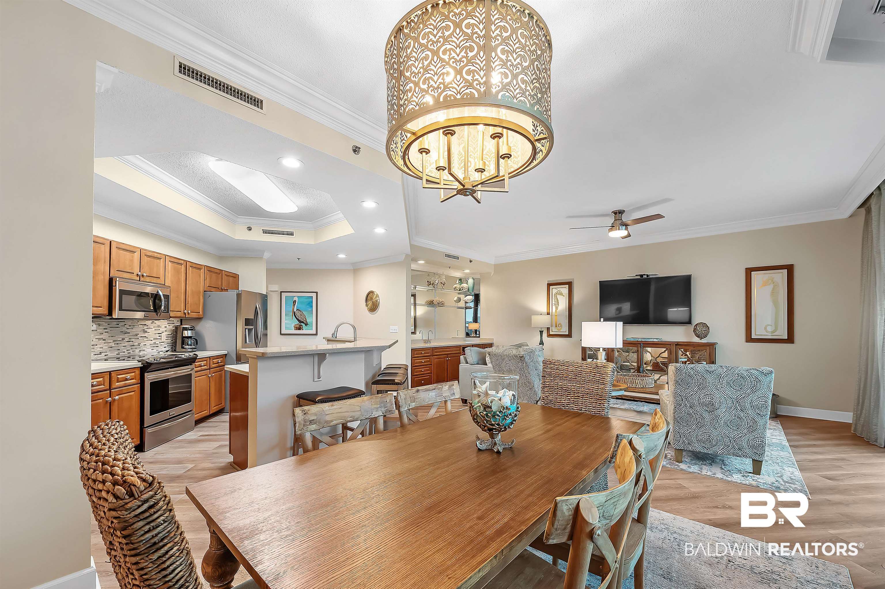 27582 Canal Road, Unit 2104 Orange Beach, AL 36561 - Photo 18 of 35 Dining space with ceiling fan with notable chandelier, crown molding, a tray ceiling, light hardwood / wood-style flooring, and sink