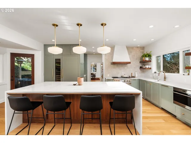 a kitchen with stainless steel appliances kitchen island granite countertop a table chairs sink and cabinets